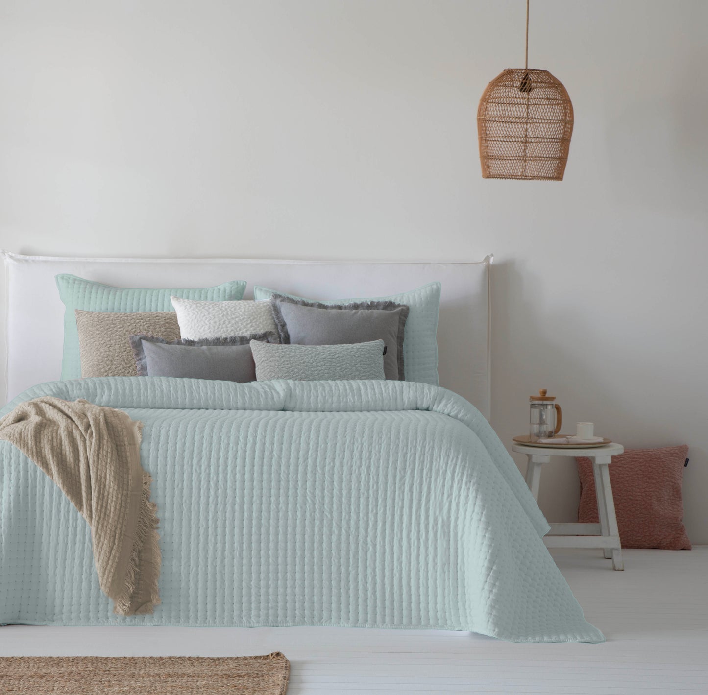 Colcha bouti lisa color verde modelo Azara de Fun & Deco con diseño de líneas verticales sobre cama de matrimonio.