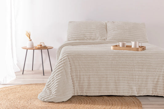 Edredón Jacquard color crudo con diseño labrado elegante en dormitorio de lujo.