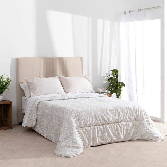 Edredón confort beige con estampado botánico blanco sobre cama en dormitorio luminoso.