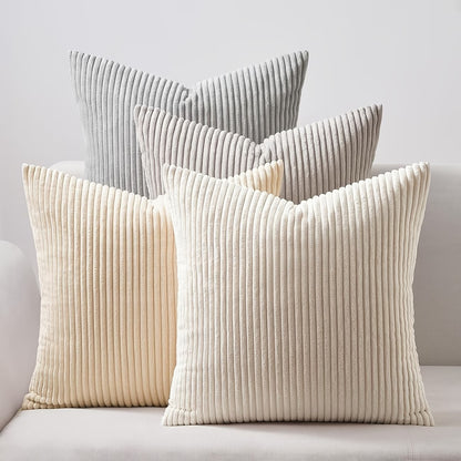 Pack de 4 fundas de cojines de 40x40 cm en colores gris, beige y blanco roto sobre un sofá moderno