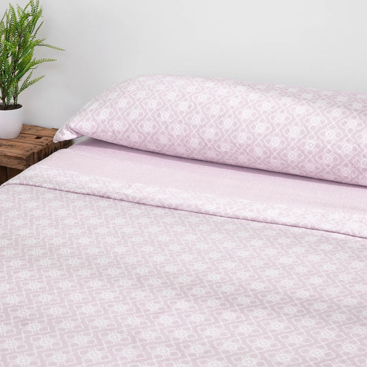 Juego de sábanas de coralina lavanda en cama con cojín a juego.