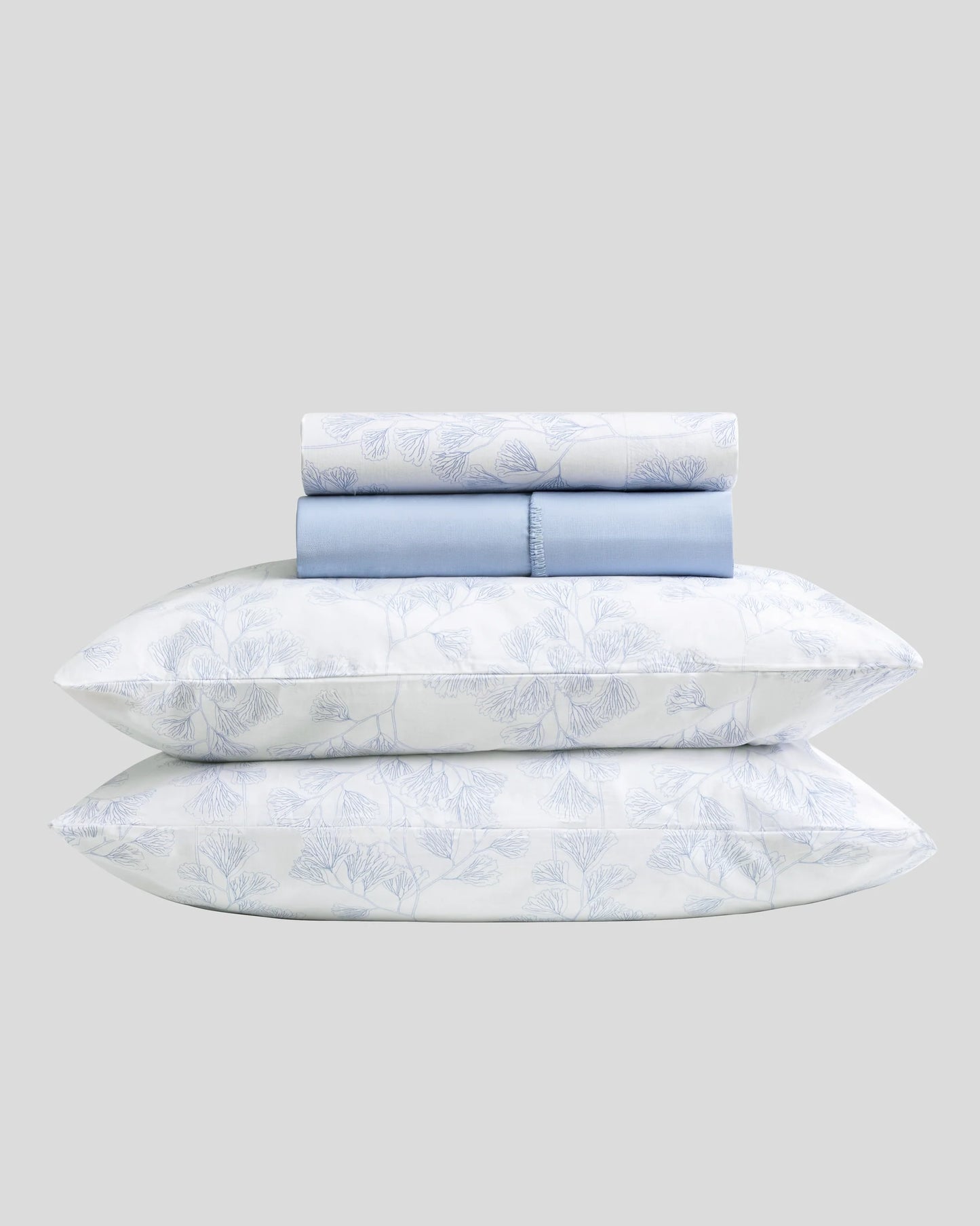 Set de sábanas de verano marca Don Algodón modelo Coralia en color azul, dobladas mostrando el estampado botánico.