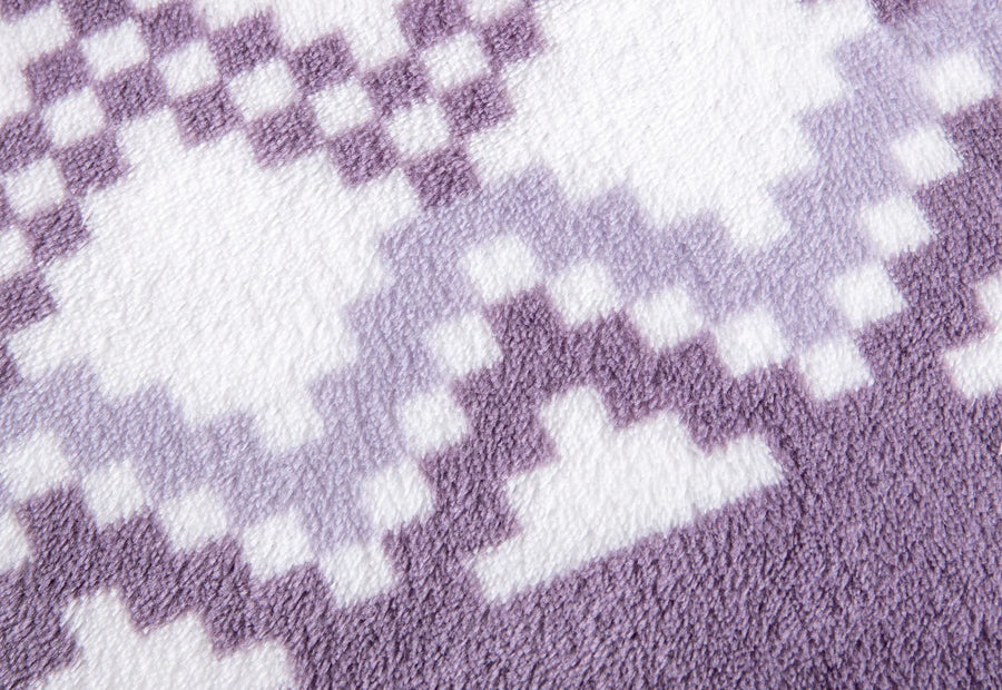 Detalle del diseño geométrico en tonos lila y blanco de las sábanas de coralina lila Idania