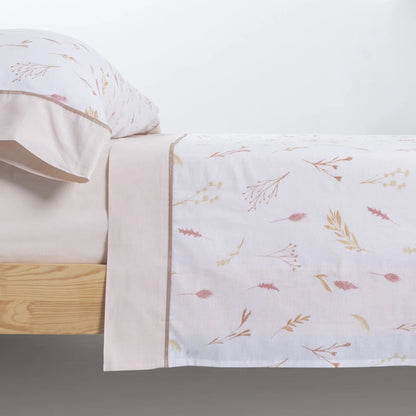 Detalle del embozo y estampado floral beige de las Sábanas de Algodón en cama de madera.