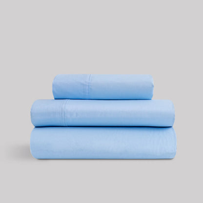 Juego de sábanas de verano color azul celeste marca Karamelo dobladas, compuestas de algodón y poliéster para cama de 90 a 180.